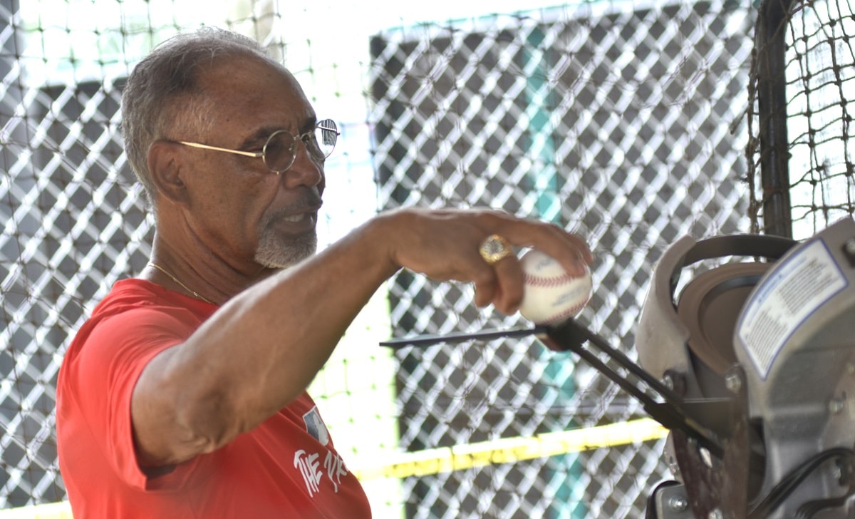 Jerry Manuel puts a baseball into a pitching machine. (Solomon Crenshaw Jr. / Alabama News Center)