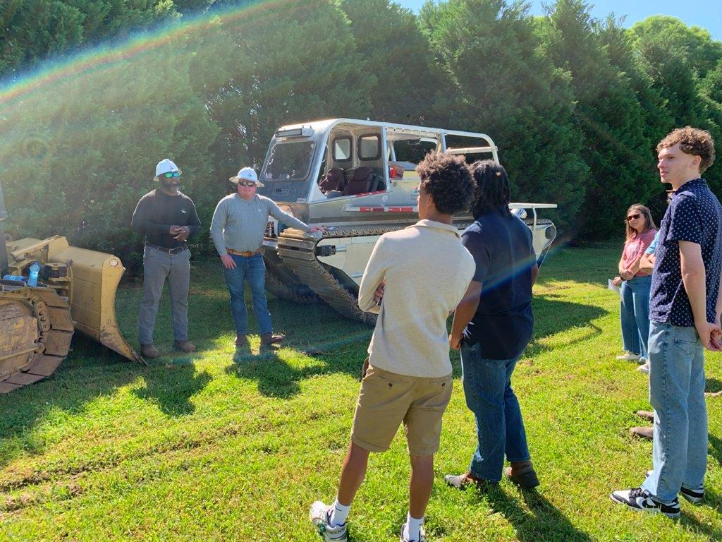 Lineworkers Bryan Link, far right, and Christopher Jackson, left, speak to students about transmission and working in rough terrains with students at Headland career day. (Teisha Wallace / Alabama News Center)