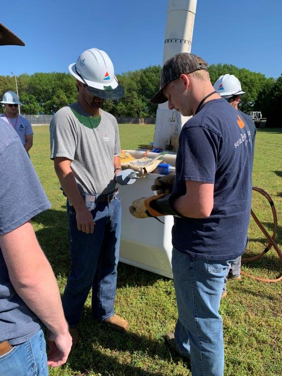 Lineman Chris Goff, left, talks to students at the mechanized equipment station at Headland career day. (Teisha Wallace / Alabama News Center)